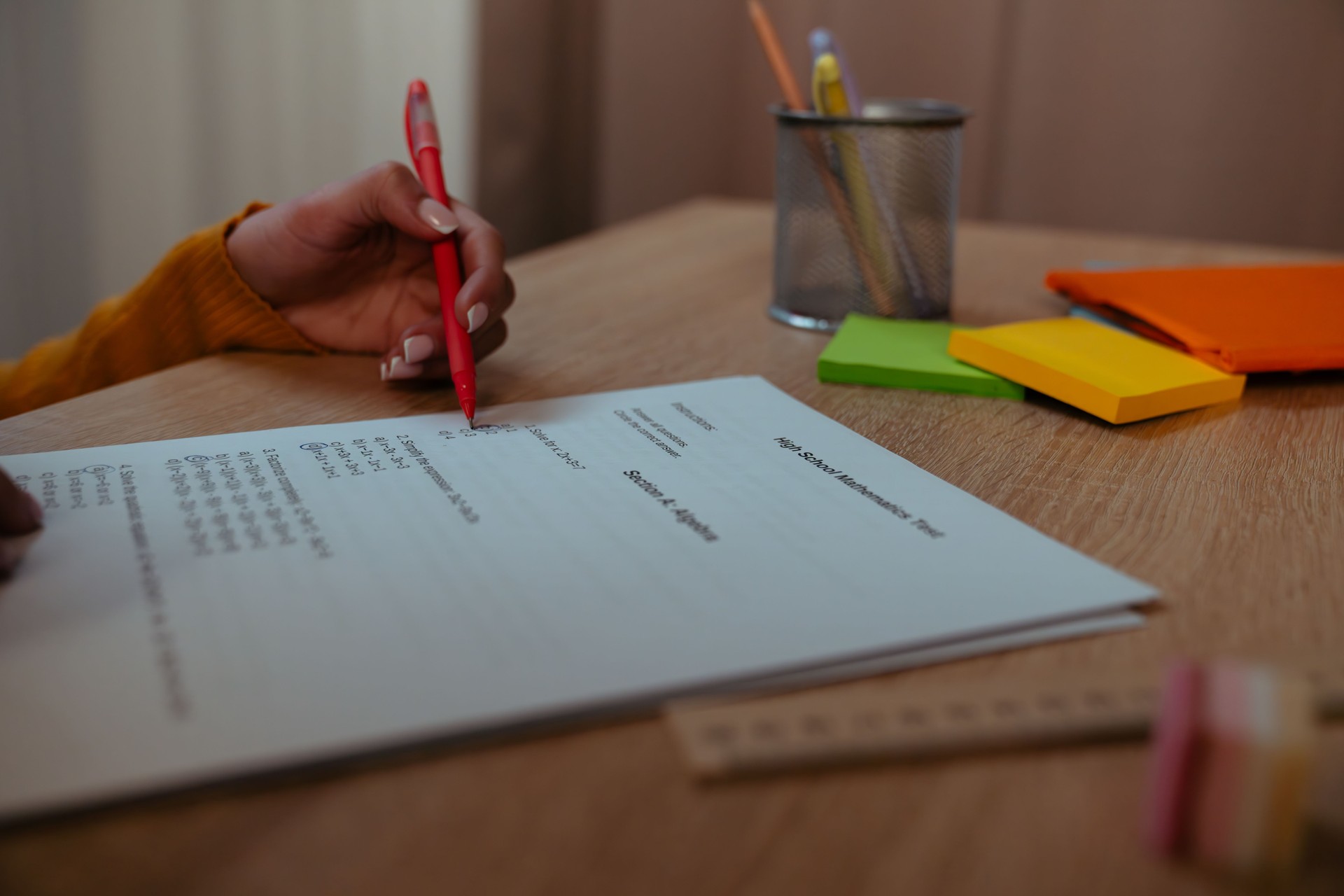 Person Reviewing High School Mathematics Test with Red Pen